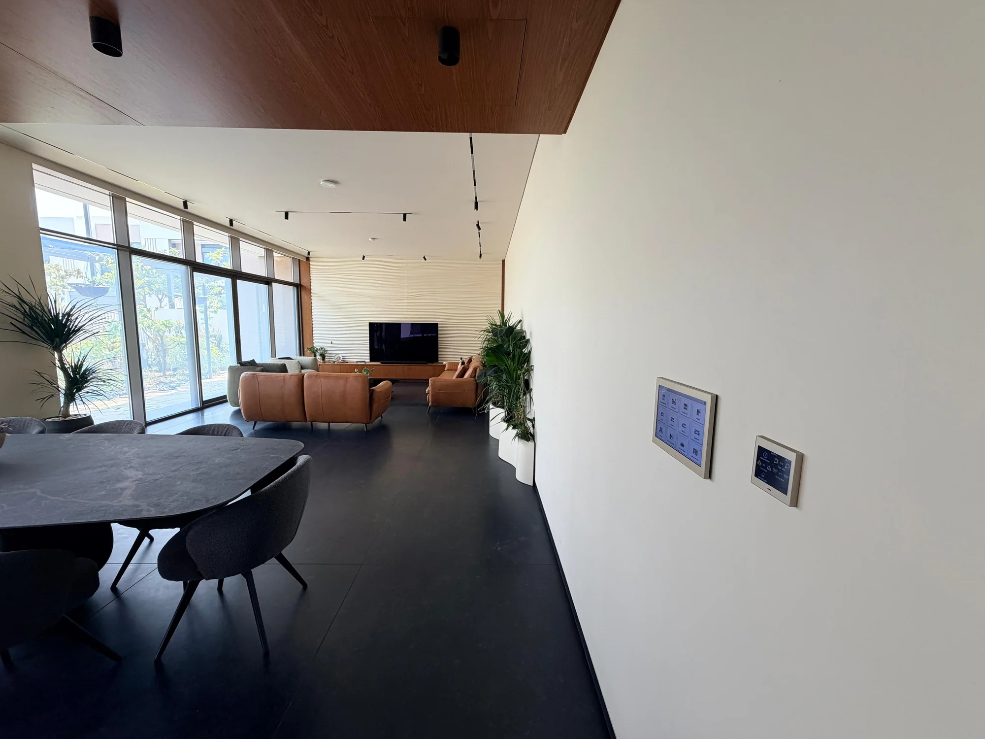 Living and dining interior with wall-mounted controls in a Dubai villa