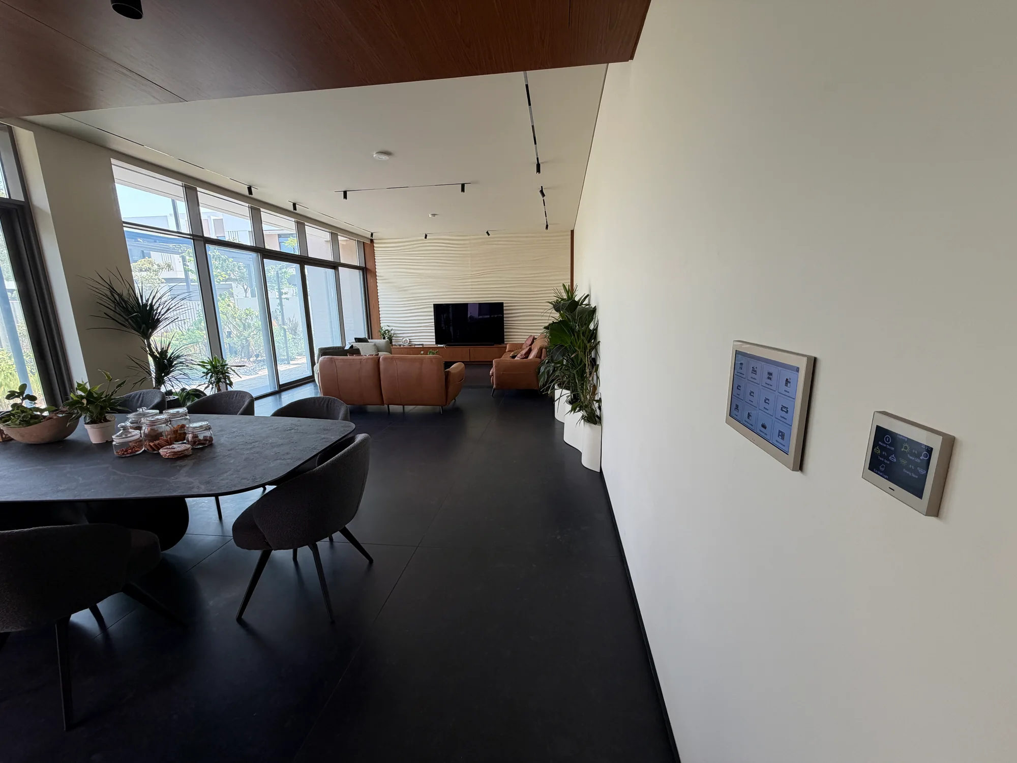Living and dining interior with two wall-mounted control panels in a Dubai villa